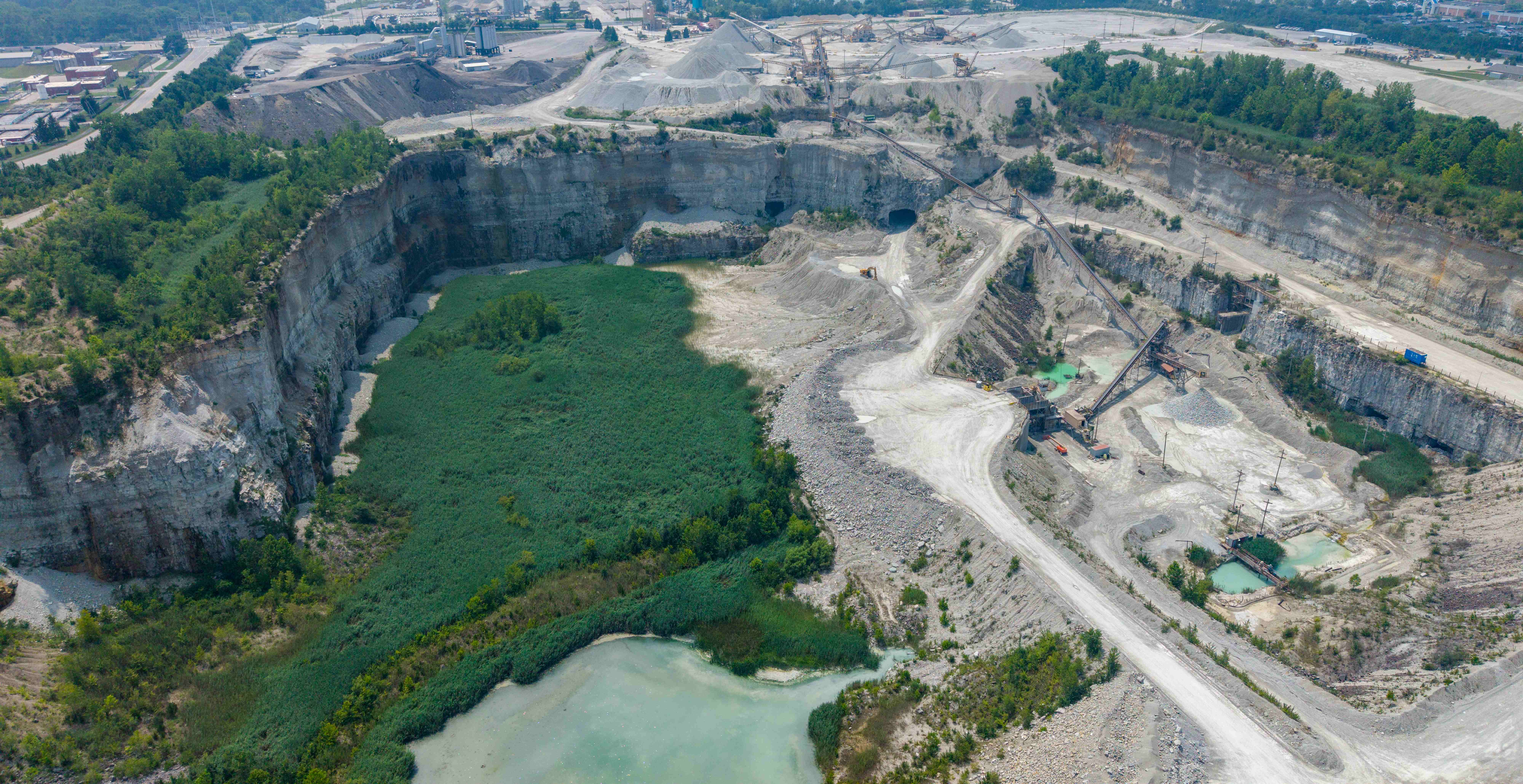Wide aerial of an active aggregate quarry showing the full pit, benches, processing plant, and haul roads for tracking site change over time