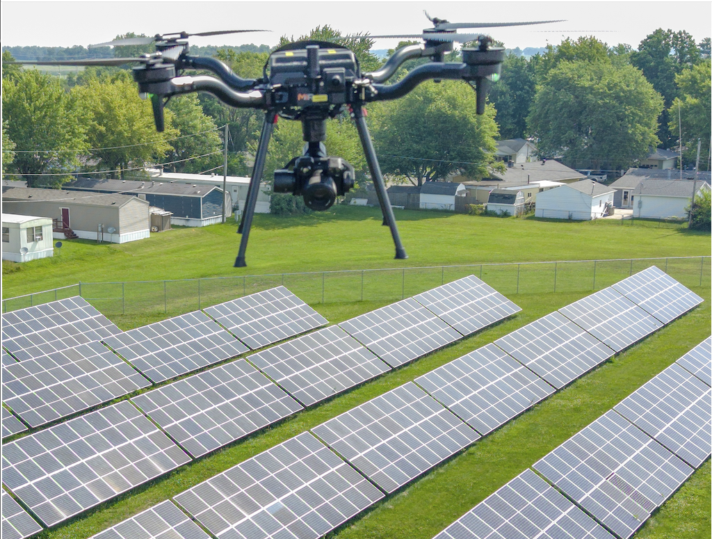 MIR Freefly Astro drone flying low over rows of ground-mounted solar panels during an autonomous thermal and RGB capture pass